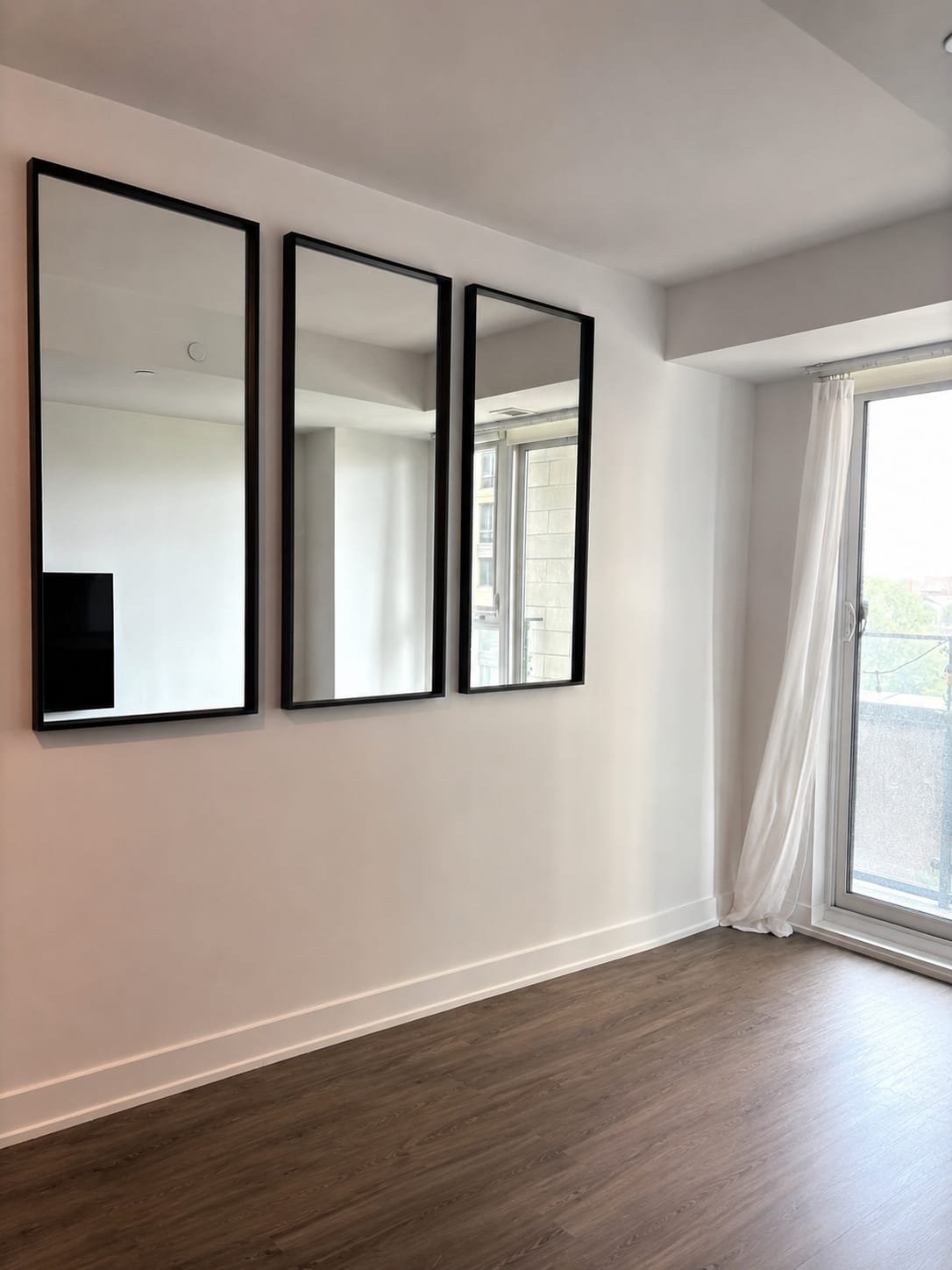 Three black-framed mirrors aligned on a living-room wall
