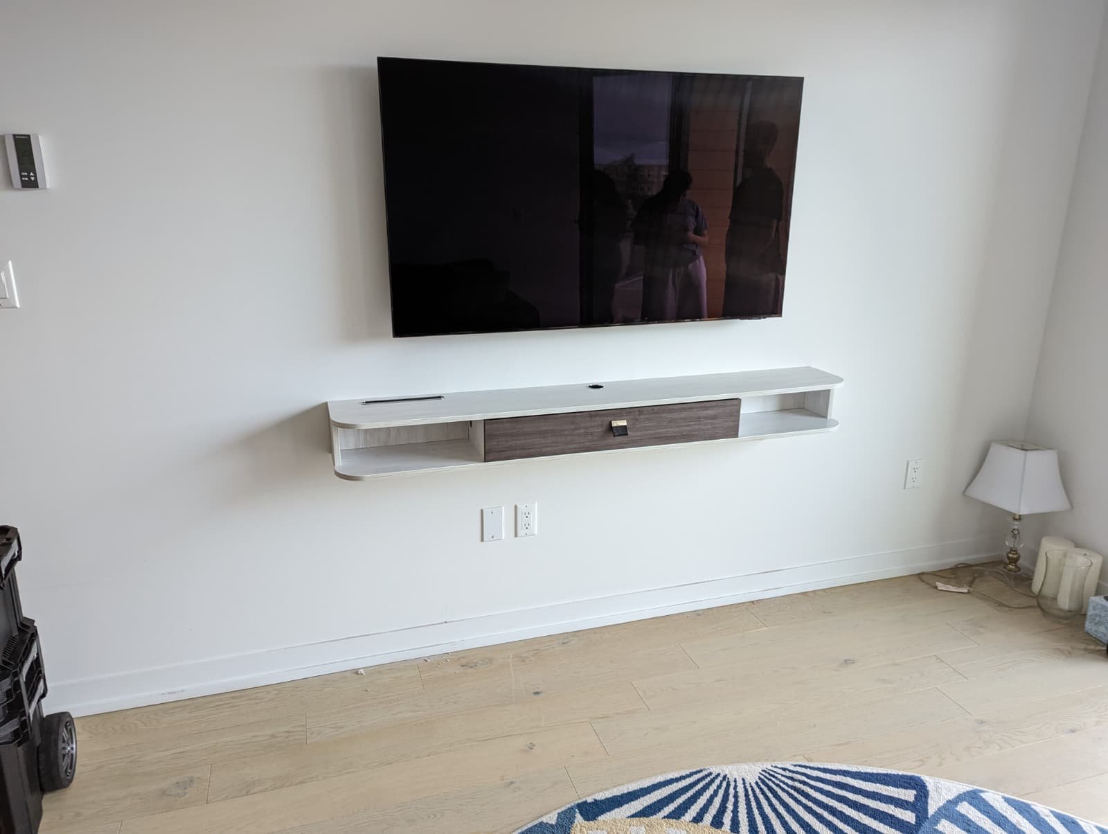 Television and floating console mounted on a white living-room wall